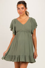 woman wearing an olive green maternity dress with flutter sleeves and a ruffled hem, showcasing her baby bump