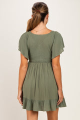 woman wearing a sage green maternity dress with flutter sleeves and a ruffled hem, back view