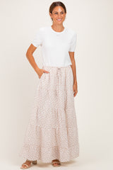 woman wearing a white short sleeve top and a long floral print maxi skirt with pockets