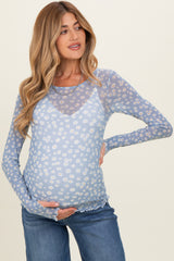 woman wearing a light blue long sleeve maternity top with floral print and holding her baby bump