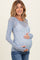woman wearing a light blue sheer maternity top with floral patterns and a visible baby bump