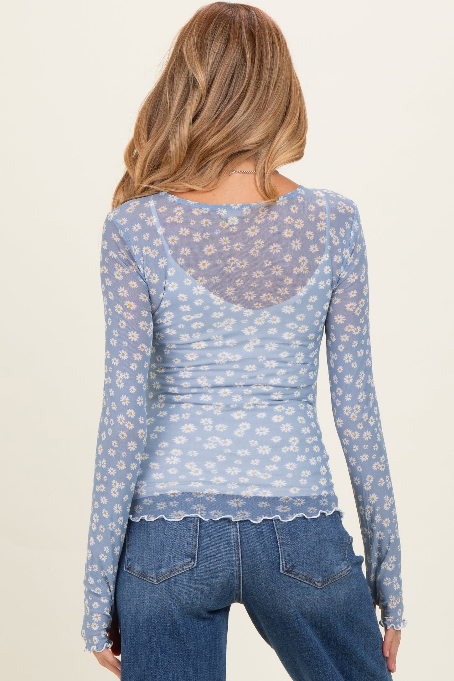 woman wearing a light blue long sleeve maternity top with a floral print and sheer back detail