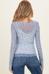 woman wearing a light blue long sleeve maternity top with a floral print and sheer back detail