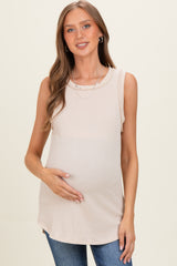 woman wearing a light beige ribbed maternity tank top and holding her baby bump
