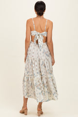 woman wearing a floral printed maxi dress with a tie back and tiered skirt, showing off the back design