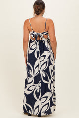 woman wearing a navy and white floral print maternity maxi dress with a tie-back detail