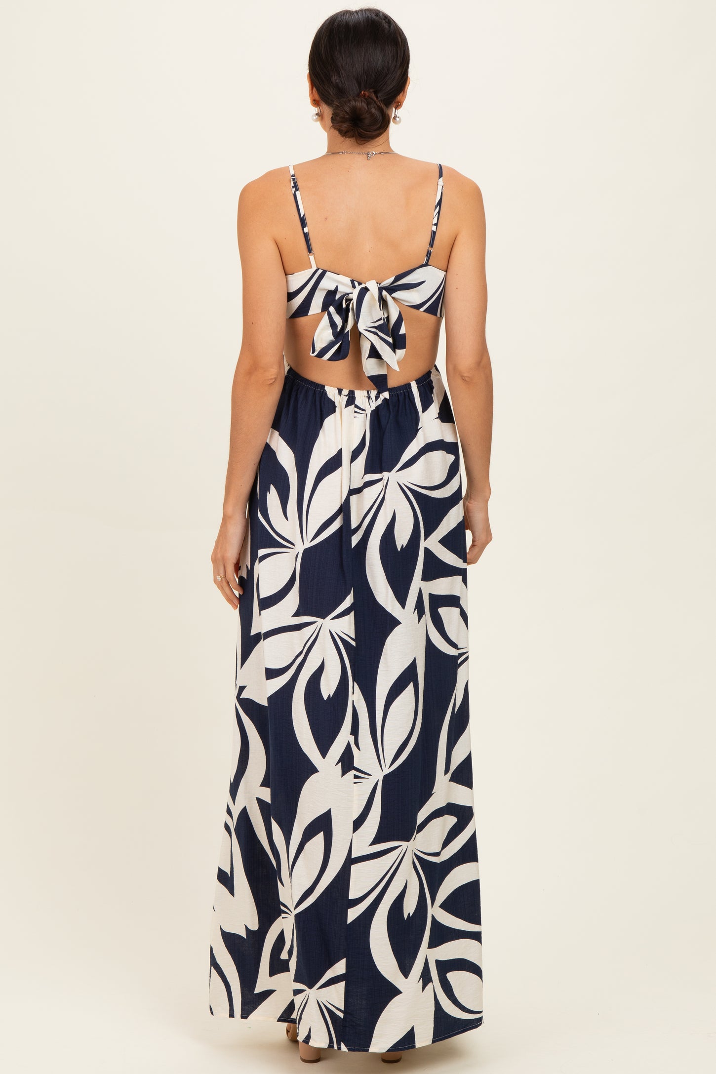 woman wearing a navy blue and white floral maxi dress with a back tie detail and open back
