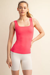 woman wearing a fitted coral square neck tank top with a slim silhouette and white athletic shorts