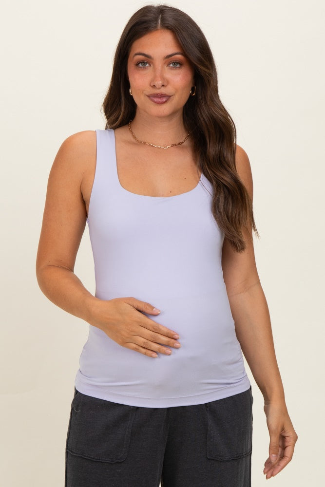 woman wearing a light lavender maternity tank top and holding her baby bump