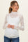 woman wearing a white lace maternity top with long sleeves and a mock neck, showing her baby bump
