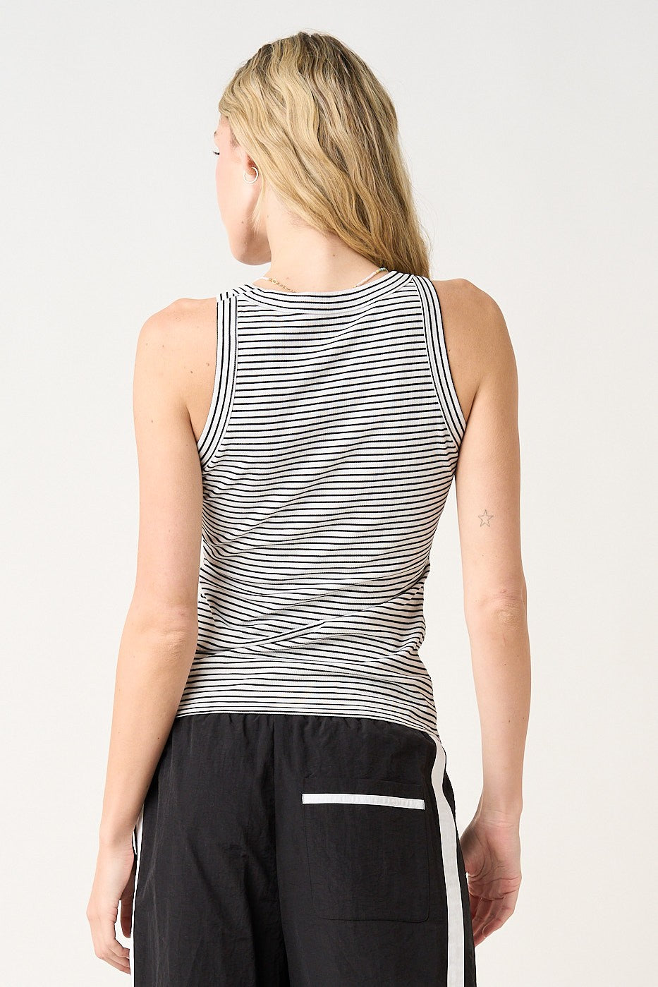 woman wearing a black and white striped sleeveless tank top, seen from the back
