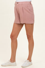 woman wearing light pink maternity shorts with pleats, styled casually with white sneakers