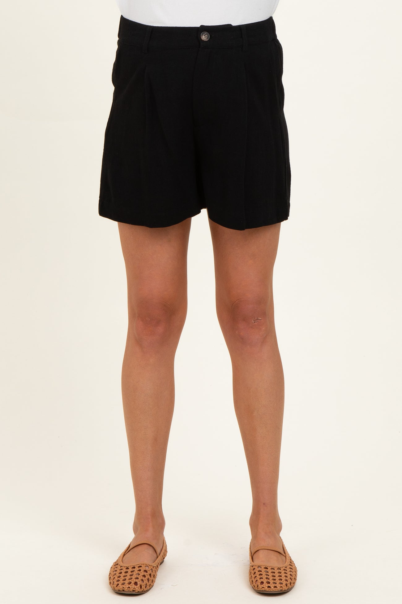woman wearing a pair of black maternity shorts with front pleats and a relaxed fit