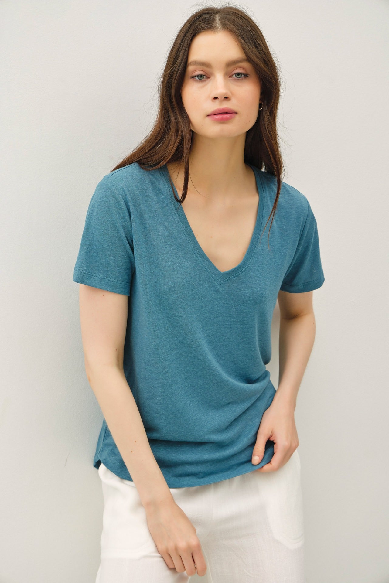 woman wearing a teal v-neck short sleeve t-shirt paired with white linen pants
