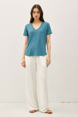woman wearing a teal short sleeve v-neck t-shirt and white wide-leg pants