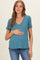 woman wearing a teal maternity top with a v-neckline and holding her baby bump