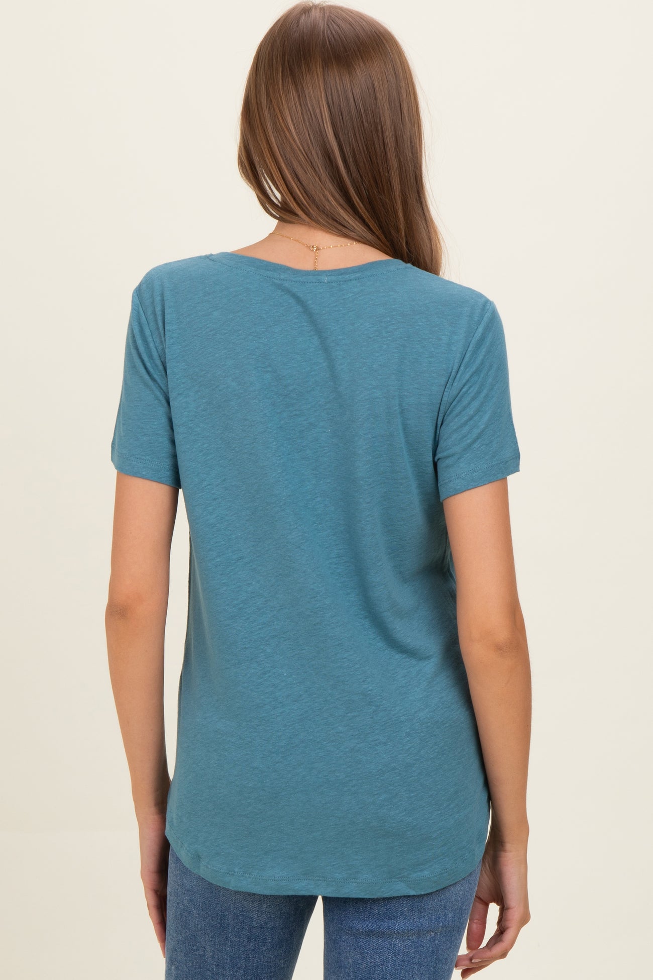 woman wearing a teal short sleeve maternity top, seen from the back, with a relaxed fit and rounded hem