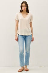 woman wearing a light pink v-neck t-shirt with short sleeves and light blue flared jeans