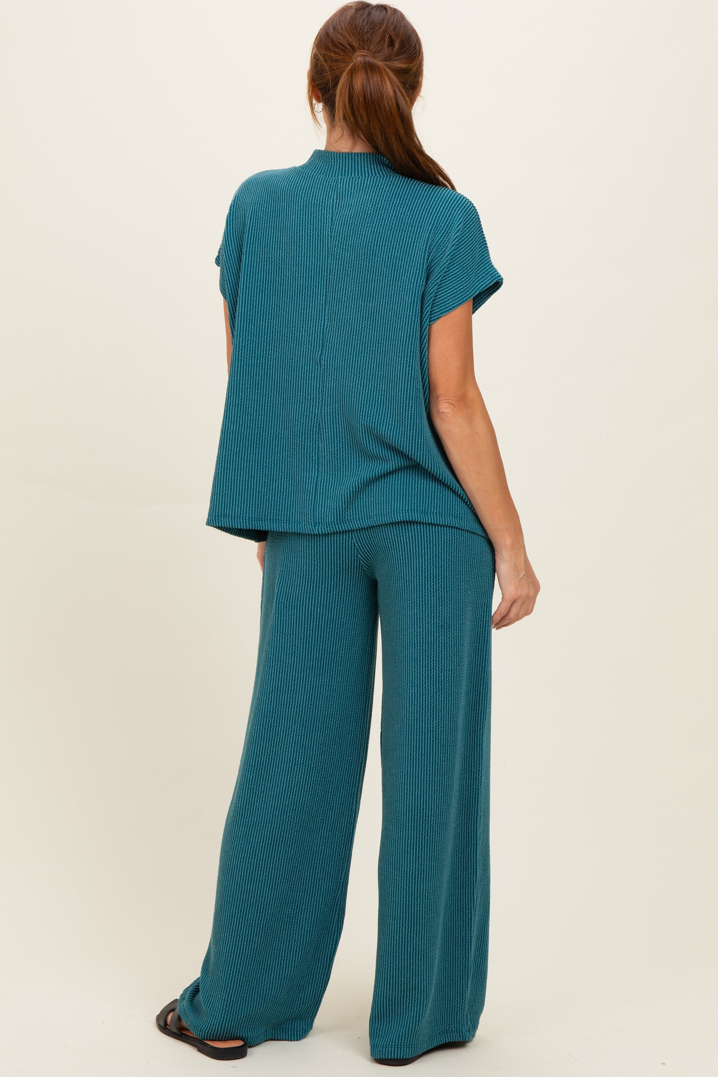 woman wearing a teal ribbed knit top and matching wide-leg pants, viewed from the back