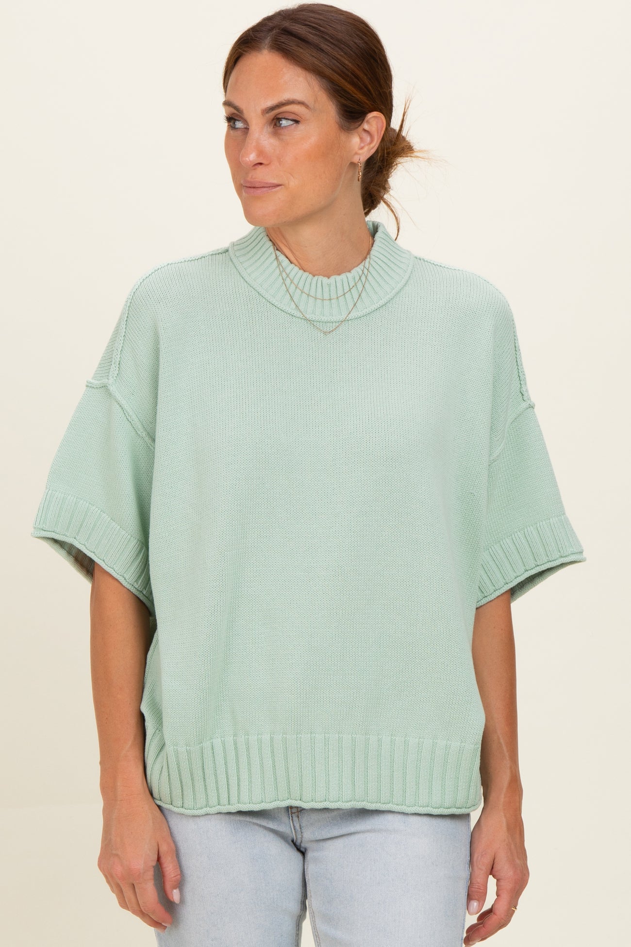 woman wearing a mint green oversized short sleeve sweater with a ribbed neckline and hem