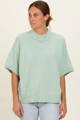 woman wearing a mint green oversized short sleeve sweater with a ribbed neckline and hem