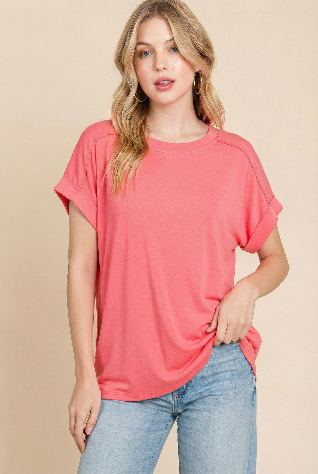 woman wearing a coral oversized t-shirt with rolled sleeves and light blue jeans