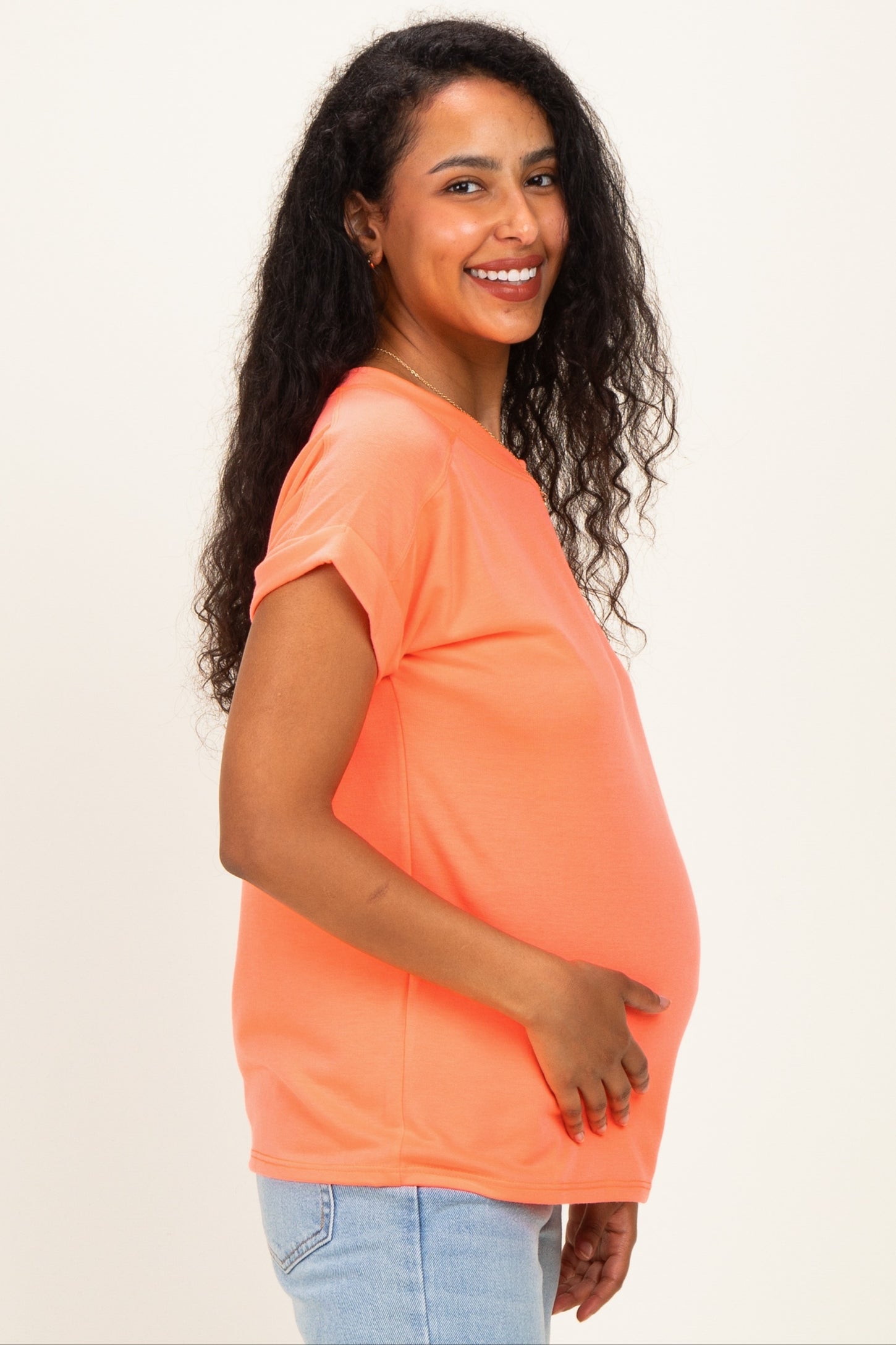 woman wearing a coral maternity t-shirt and holding her baby bump