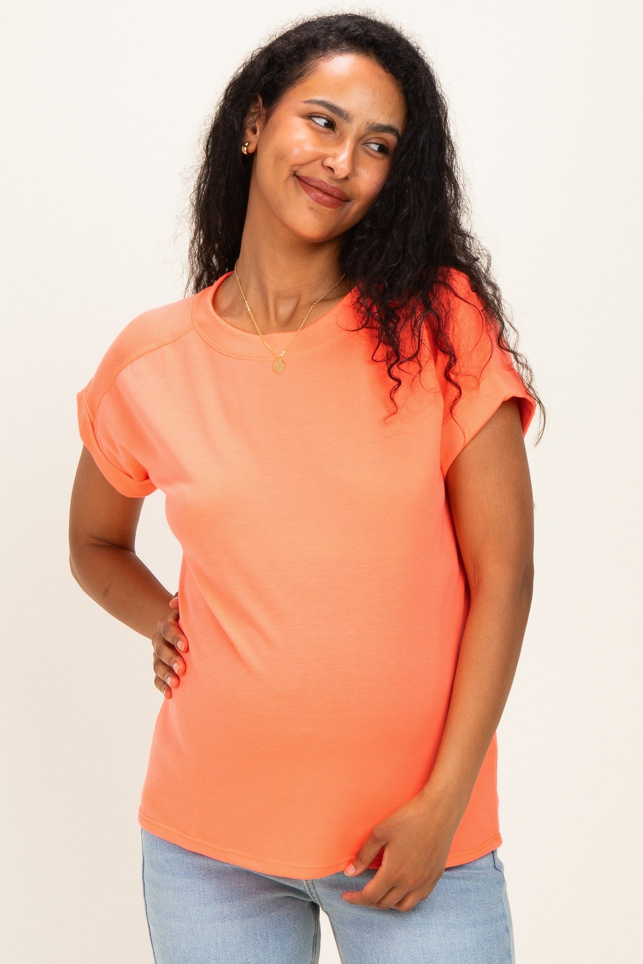 woman wearing a bright orange maternity top with short sleeves and a relaxed fit, showing her baby bump