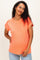 woman wearing a bright orange maternity top with short sleeves and a relaxed fit, showing her baby bump