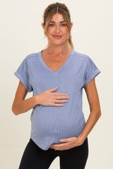 woman wearing a light blue short sleeve maternity top and holding her baby bump
