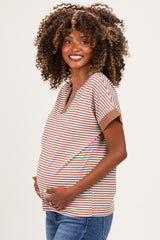 woman wearing a striped brown and cream maternity top, gently cradling her baby bump