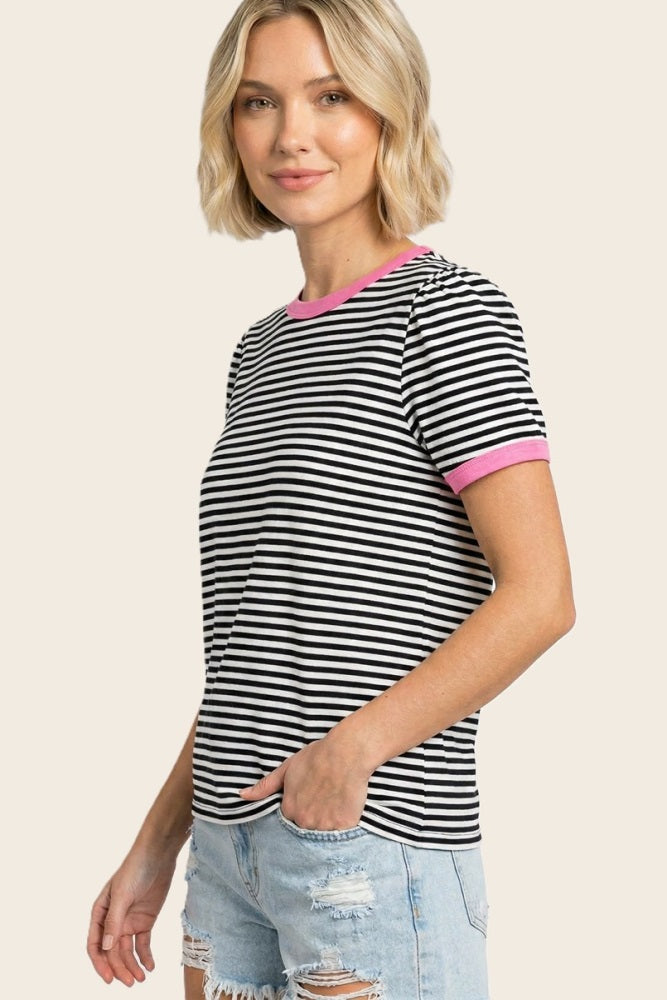 woman wearing a black and white striped t-shirt with pink sleeves and blue distressed denim shorts