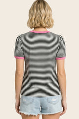 woman wearing a black and white striped short sleeve shirt with pink trim, facing away, paired with denim shorts