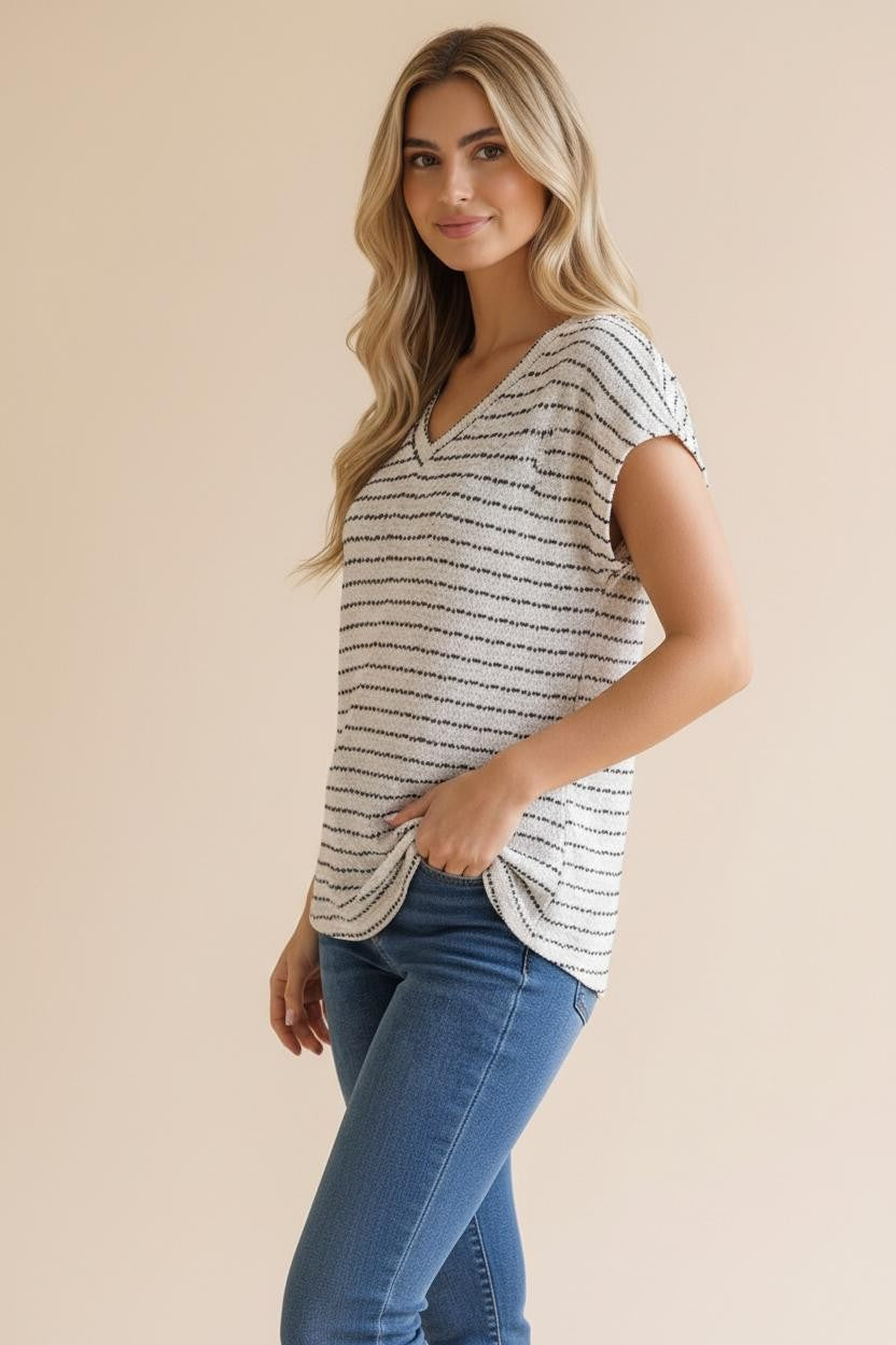 woman wearing a striped short sleeve top with a V-neck and side knot detail, paired with blue jeans