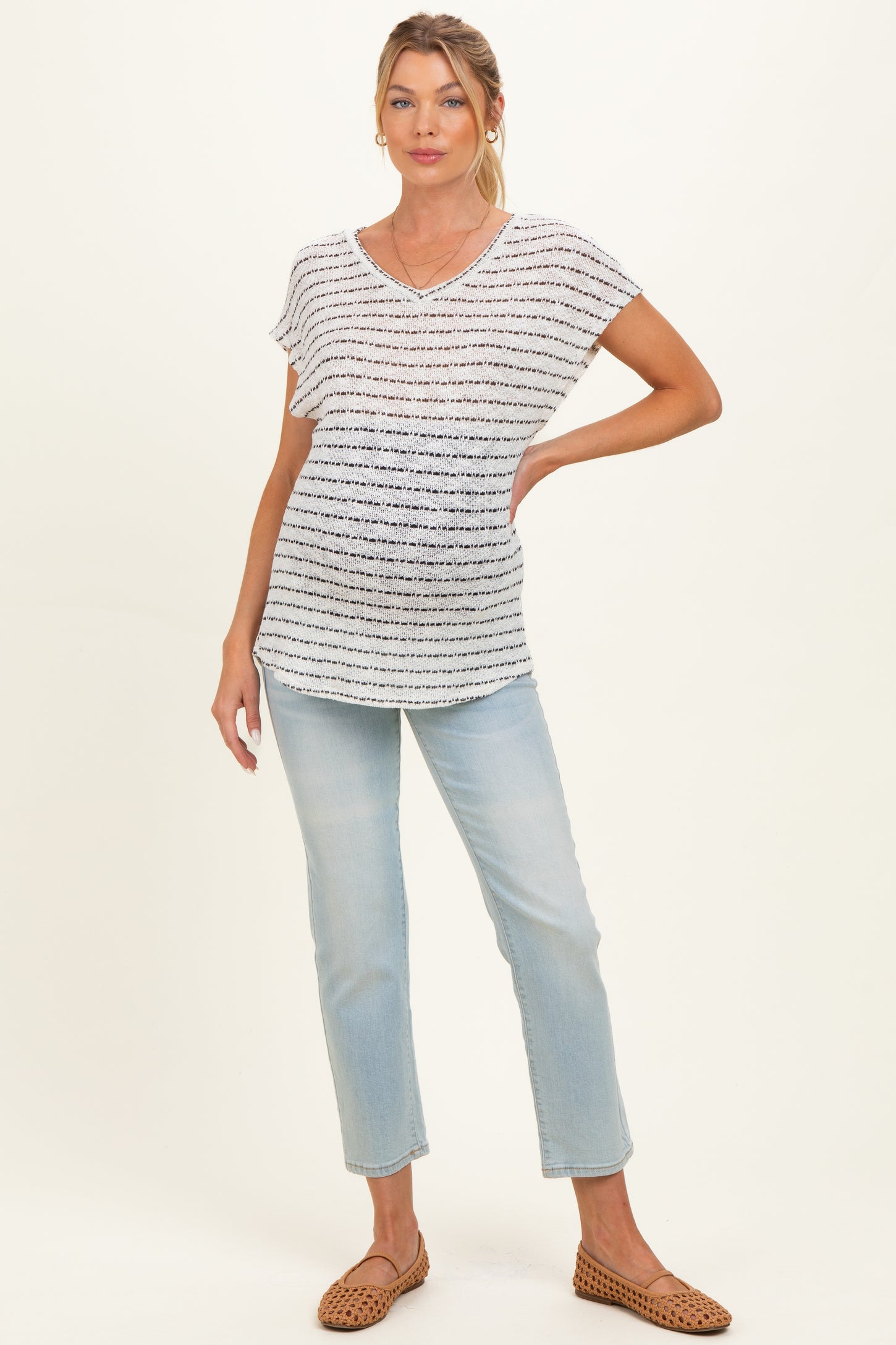 woman wearing a striped maternity top with short sleeves and a gathered waist, paired with light blue jeans