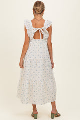 woman wearing a white floral maternity dress with ruffled straps and an open back, showing a baby bump