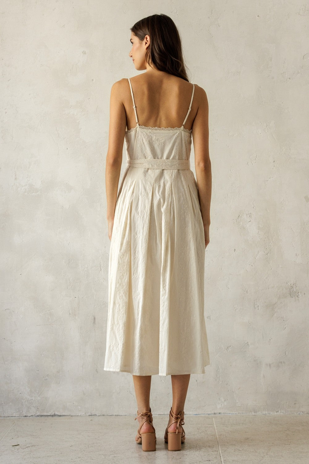 woman wearing a white midi dress with spaghetti straps and a fitted bodice, displaying a back view