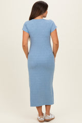 woman wearing a light blue maternity maxi dress, standing with her back to the camera, highlighting the fitted style