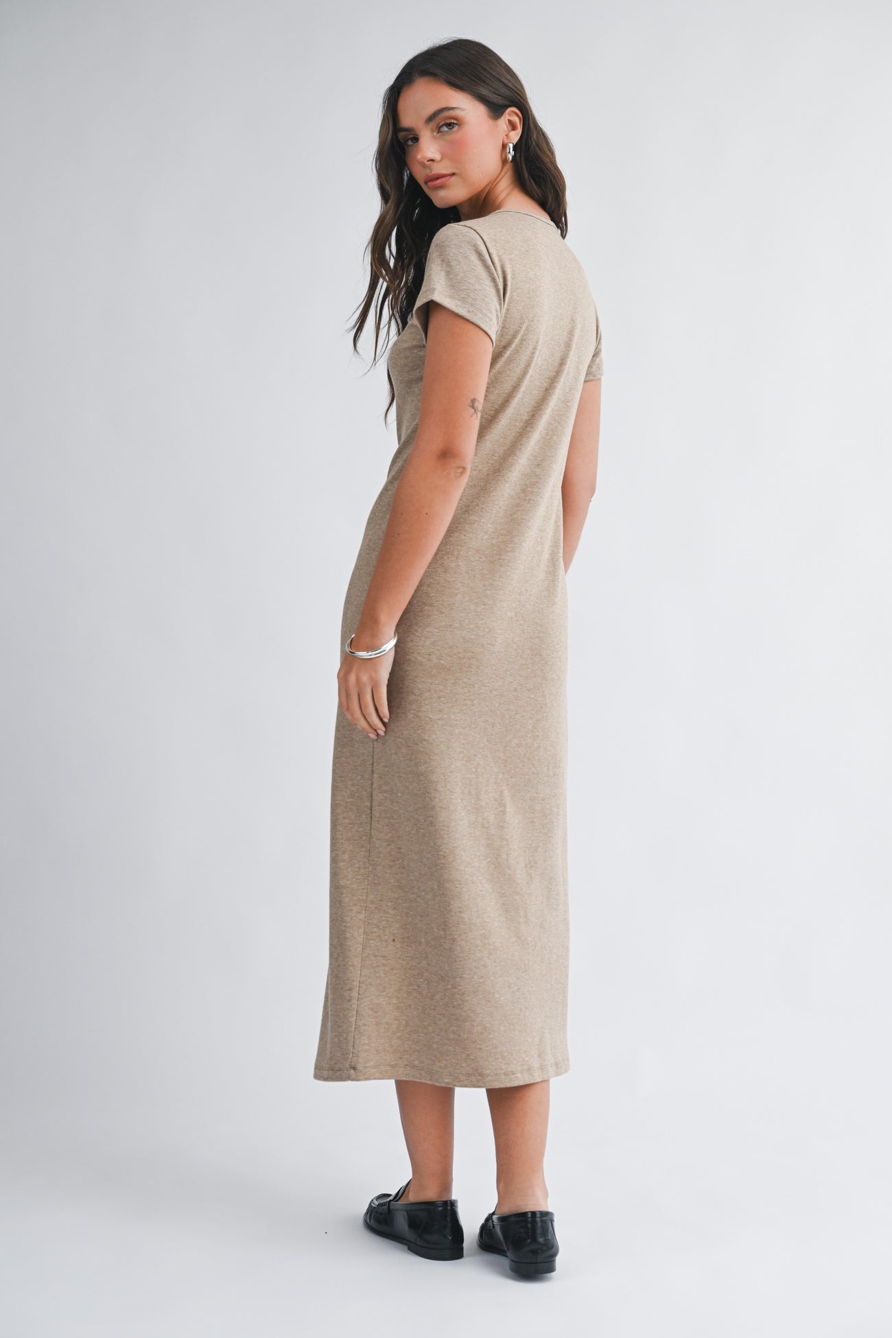woman wearing a short sleeve tan maxi dress, shown from the back, with her hair down and black shoes