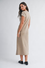 woman wearing a short sleeve tan maxi dress, shown from the back, with her hair down and black shoes