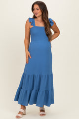 woman wearing a blue maternity maxi dress with ruffle straps and a smocked bodice, showcasing her baby bump