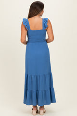 woman wearing a blue maternity maxi dress with ruffle straps and a tiered skirt, showing her back