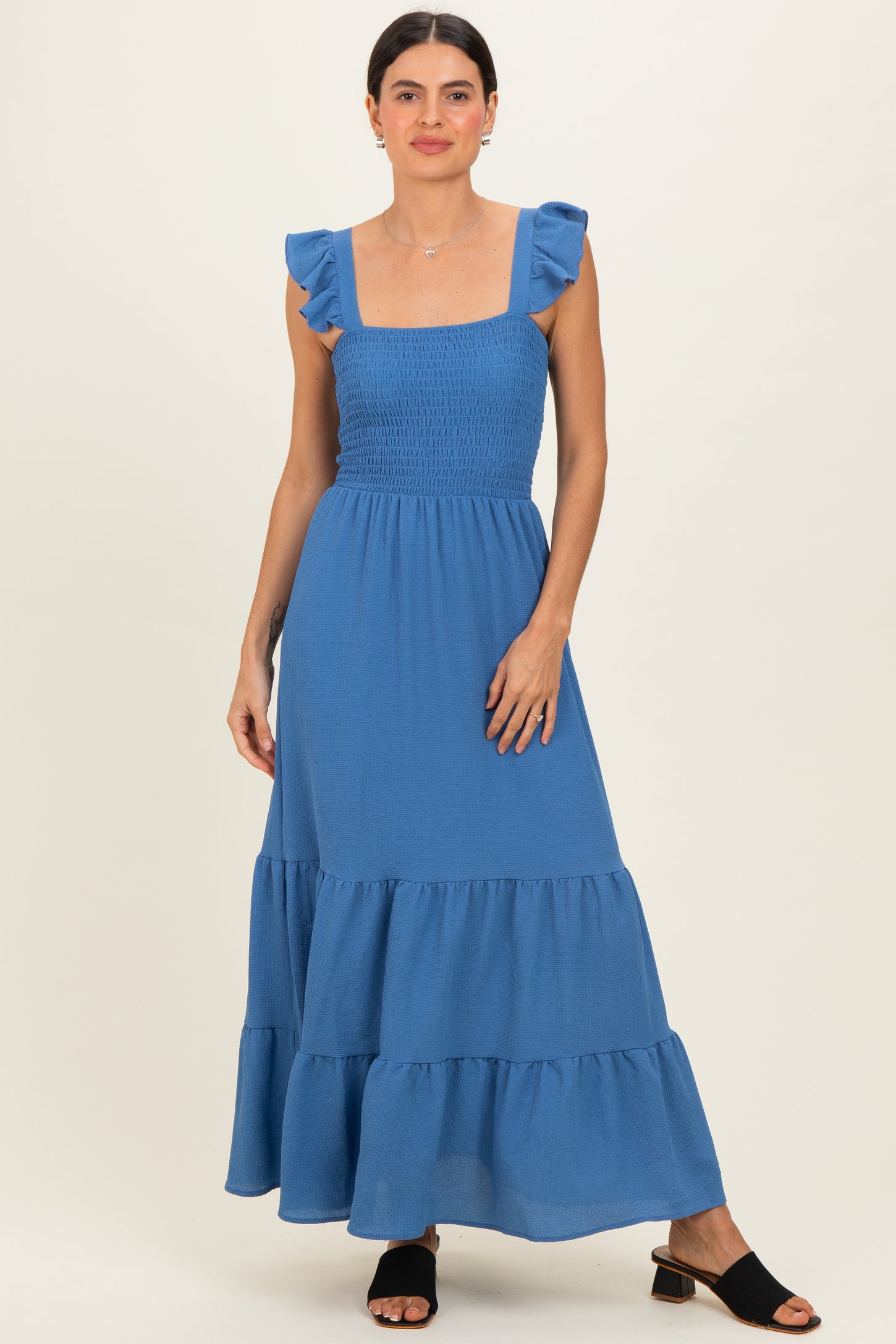 woman wearing a blue maxi dress with ruffle straps and a tiered skirt
