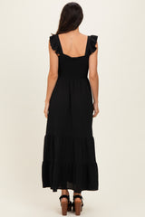 woman wearing a black maxi dress with ruffled straps and a smocked bodice, shown from the back