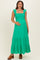 woman wearing a bright green maternity maxi dress with ruffle sleeves and a smocked bodice, showing her baby bump