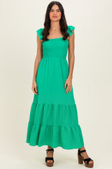 woman wearing a bright green smocked maxi dress with ruffle sleeves and tiered skirt, standing confidently
