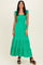woman wearing a bright green smocked maxi dress with ruffle sleeves and tiered skirt, standing confidently