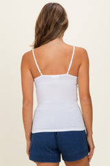 woman wearing a white fitted camisole top and blue denim shorts, viewed from the back