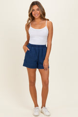 woman wearing a white tank top and denim blue shorts with side pockets