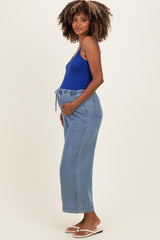 woman wearing a blue maternity tank top and light blue wide-leg pants with an elastic waistband and tie detail, showcasing her baby bump